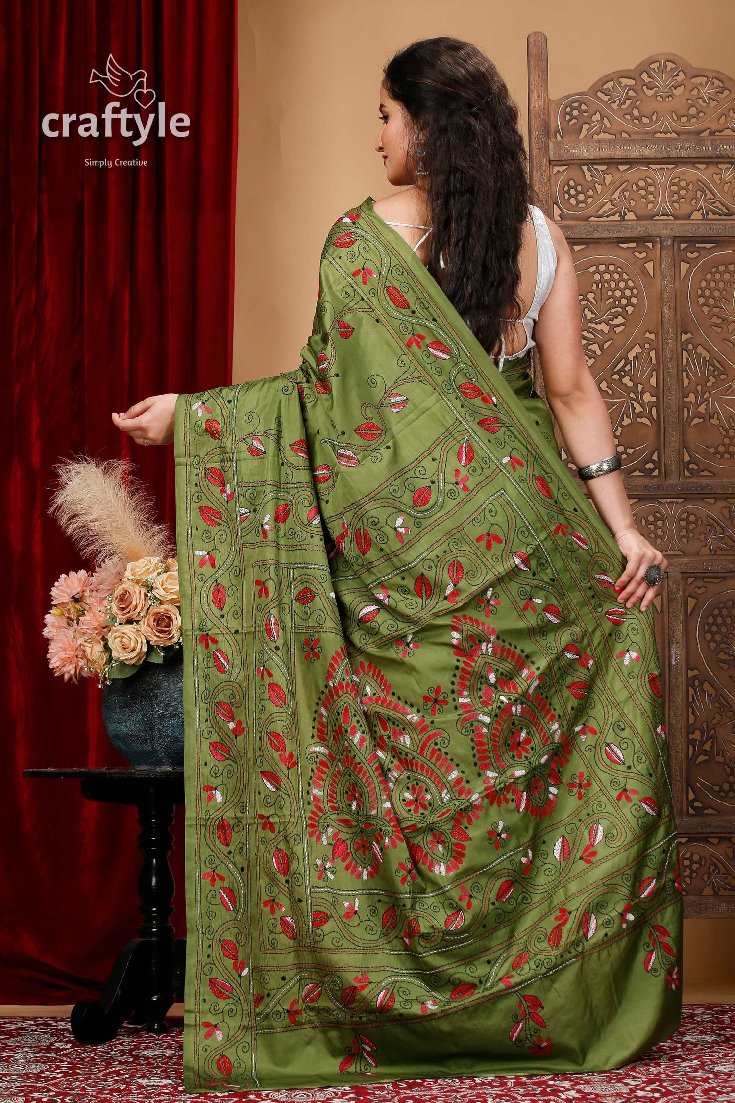 a woman wearing a green sari with red flowers on it