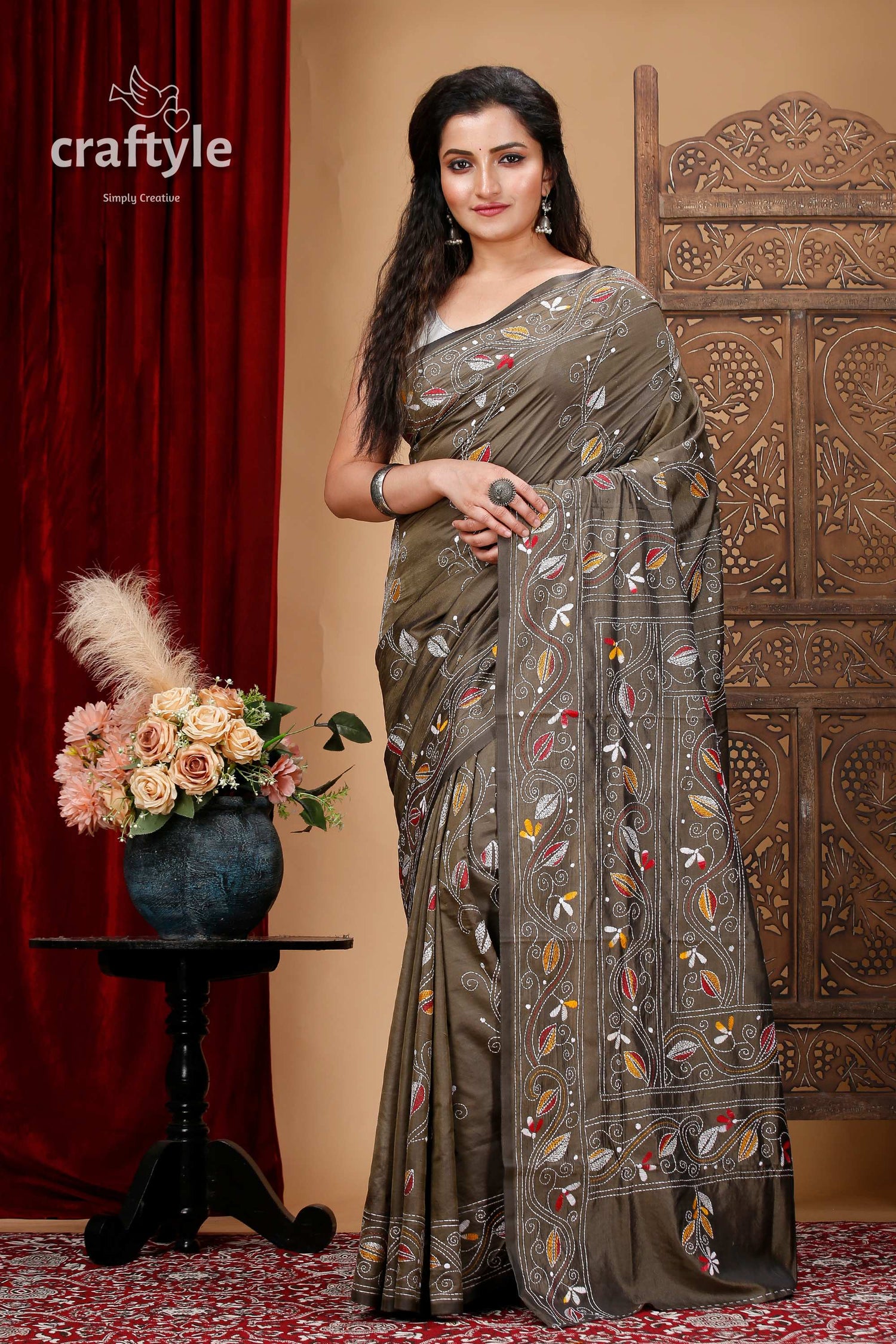 a woman in a sari standing in front of a red curtain