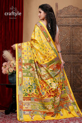 a woman in a yellow sari standing in front of a red curtain