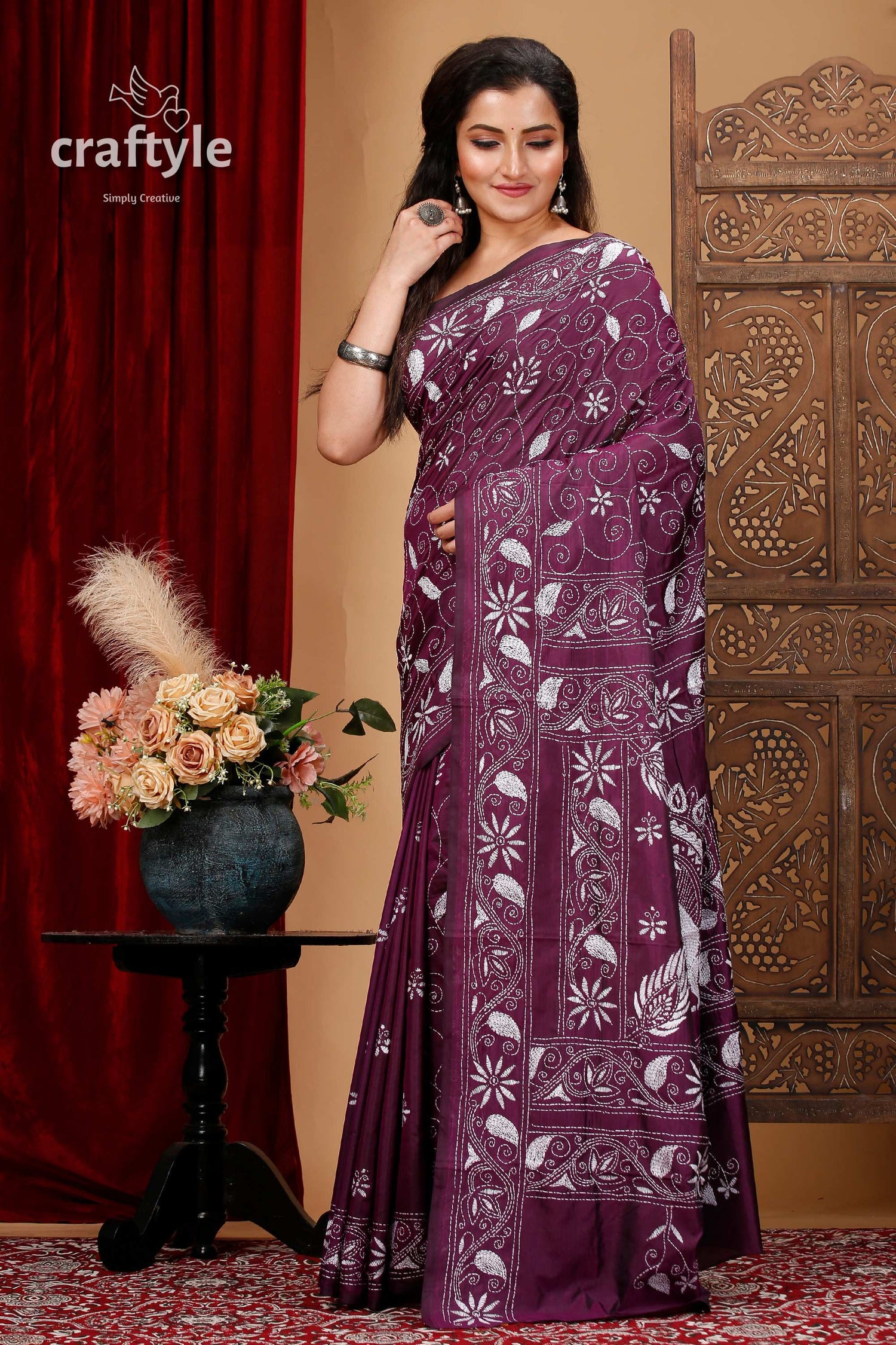 a woman in a purple sari standing in front of a red curtain