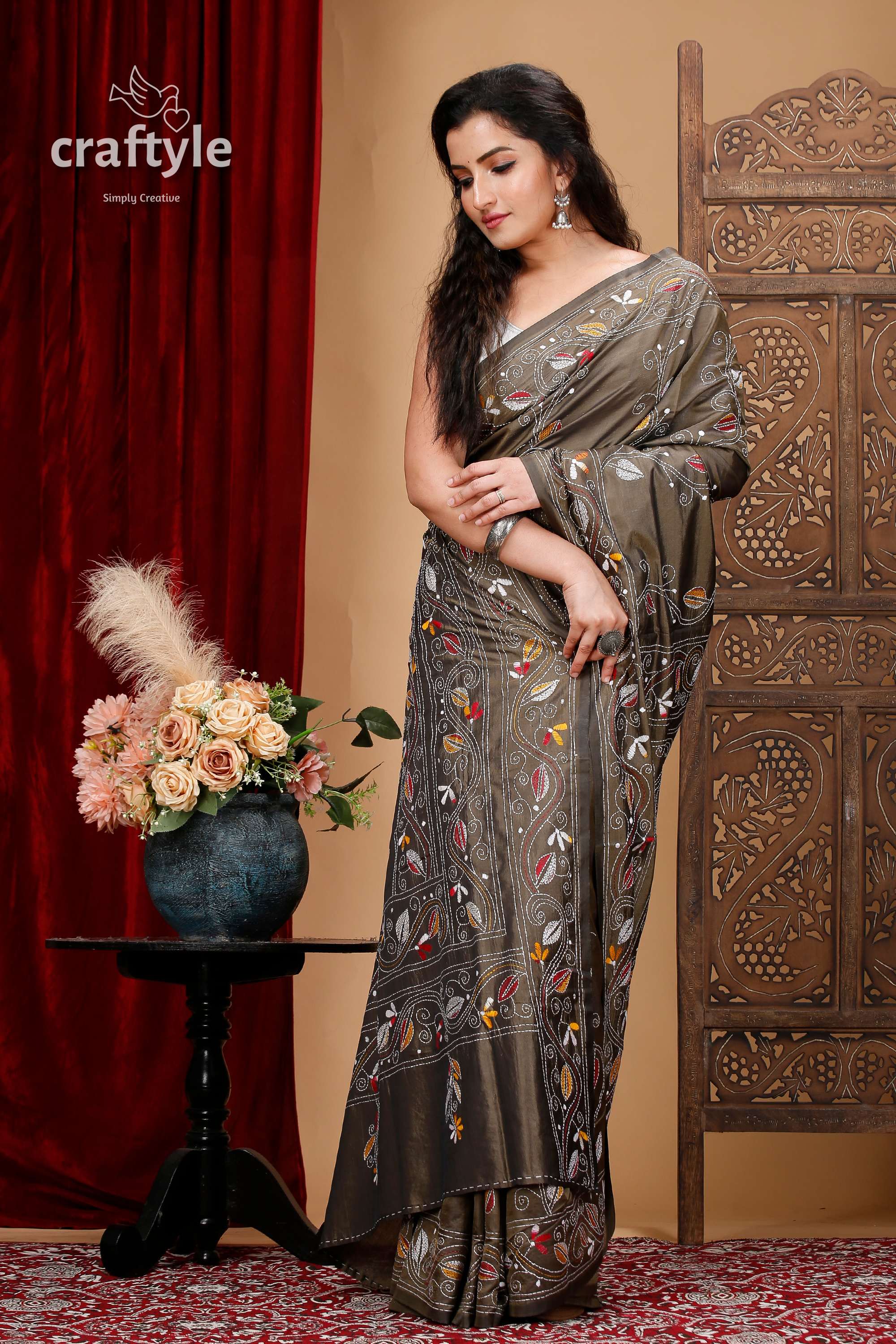 a woman in a sari standing next to a vase of flowers