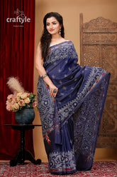 a woman in a blue sari standing in front of a red curtain