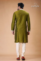 a man in a green sherwa with white pants