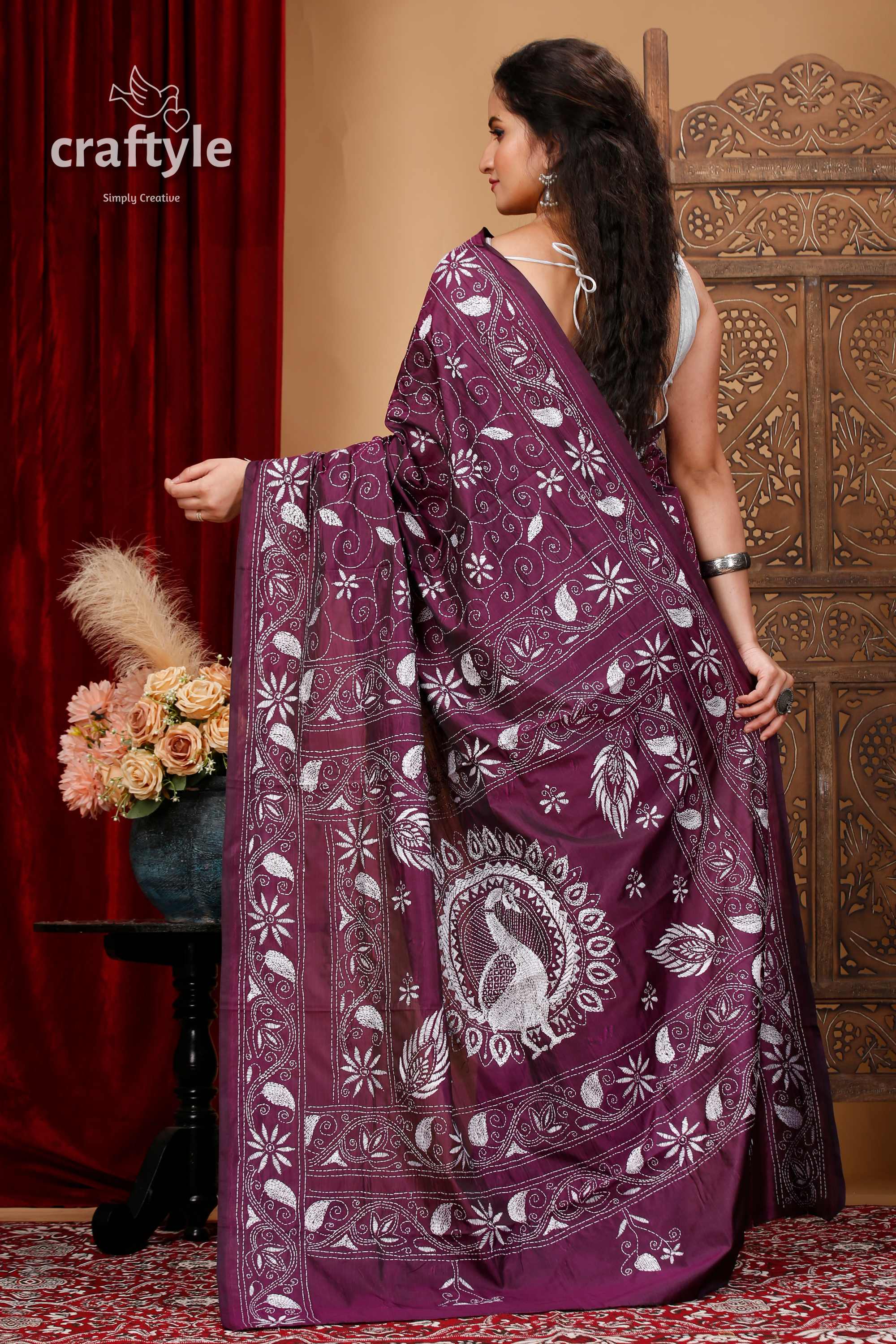 a woman in a purple sari standing in front of a red curtain