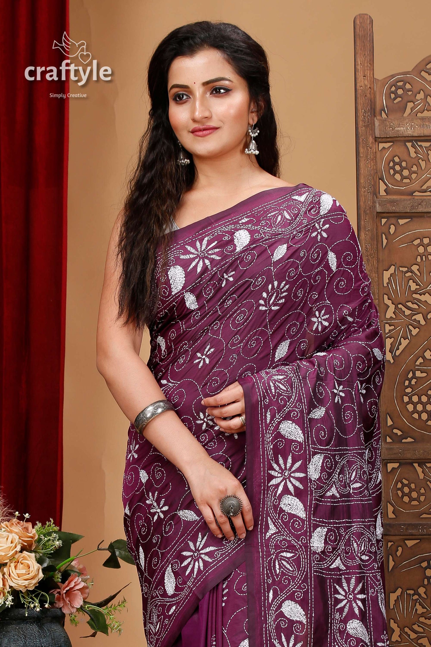 a woman wearing a purple sari with white flowers on it