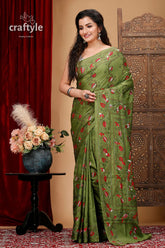 a woman in a green sari standing next to a vase of flowers