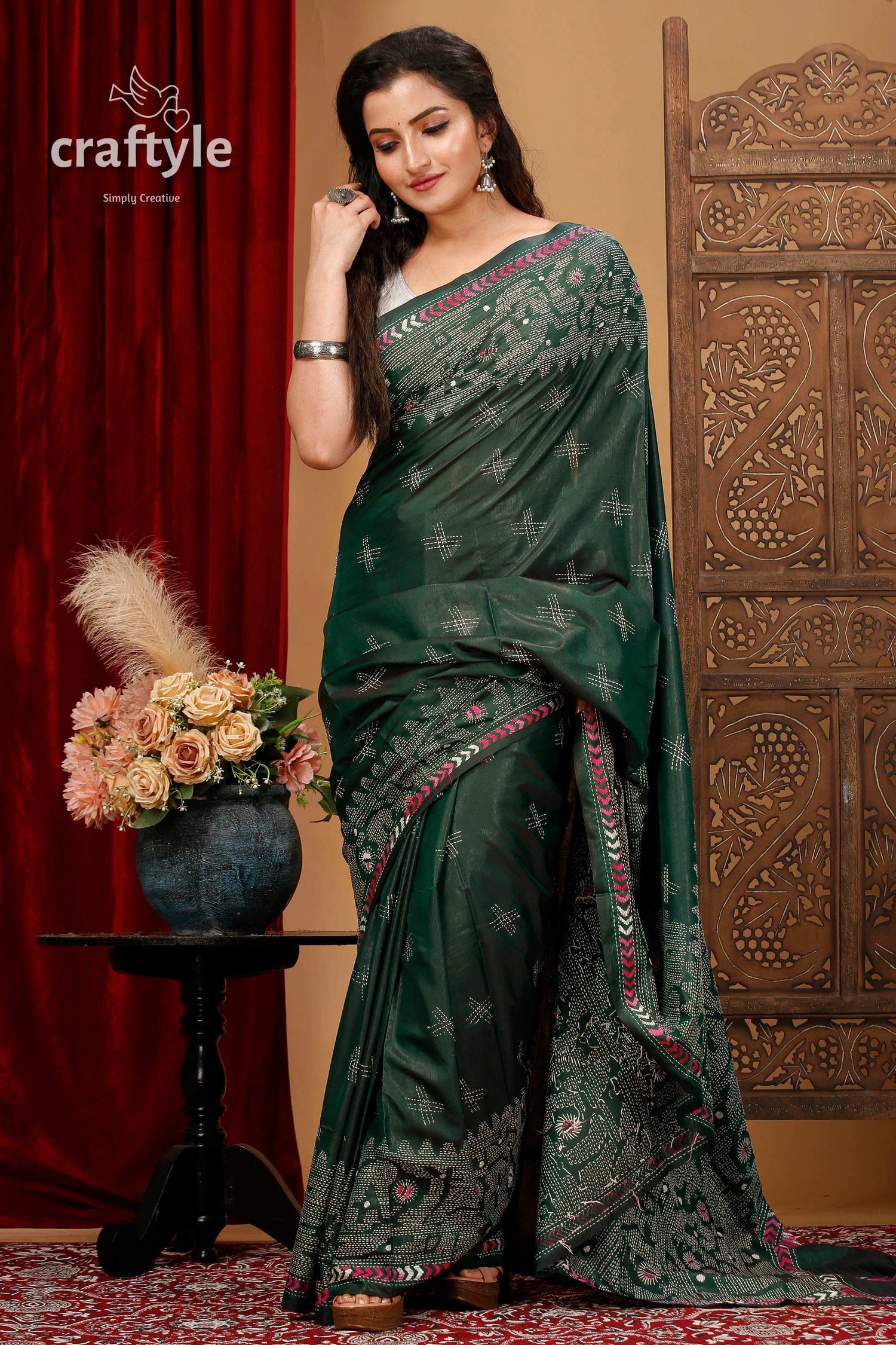 a woman in a green sari standing in front of a red curtain