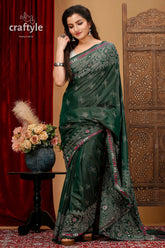 a woman in a green sari standing in front of a red curtain