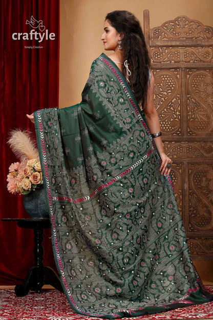 a woman in a green sari standing in front of a red curtain